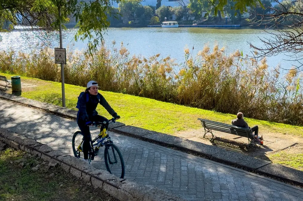 Una persona disfruta haciendo deporte junto a la orilla del río Guadalquivir a su paso por Sevilla, este sábado.