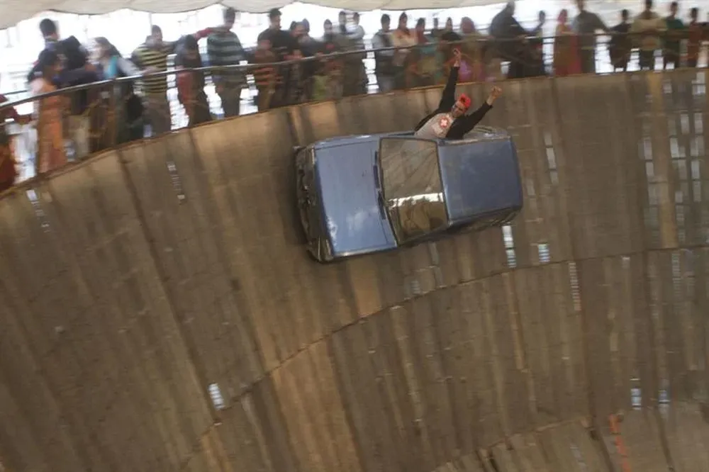 India- ﻿﻿Un hombre realiza una acrobacia con un coche en el muro de la muerte colocado en una feria en Srinagar