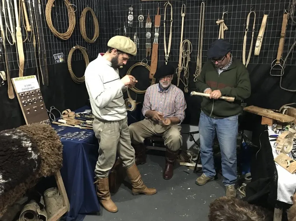 Tres de los guasqueros que exhiben su trabajo artesanal en la Rural del Prado.