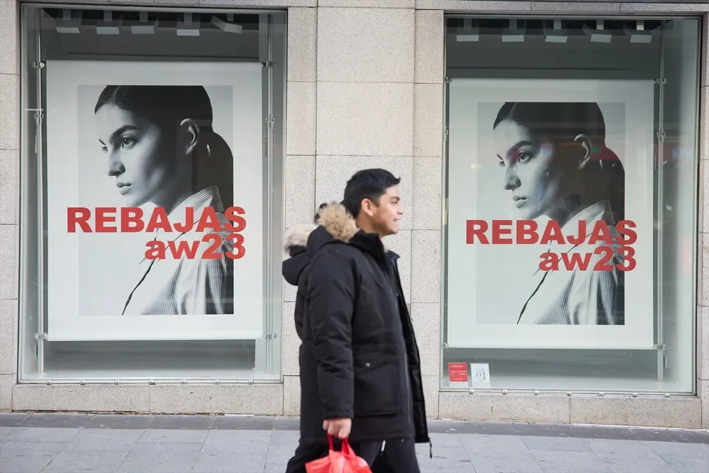Una hombre camina delante de un escaparate anunciando las rebajas, en el centro de Madrid.