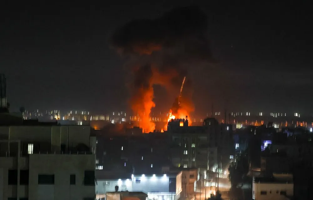 Las explosiones iluminan el cielo nocturno sobre los edificios en la ciudad de Gaza mientras las fuerzas israelíes bombardean el enclave palestino, a principios del 16 de junio de 2021