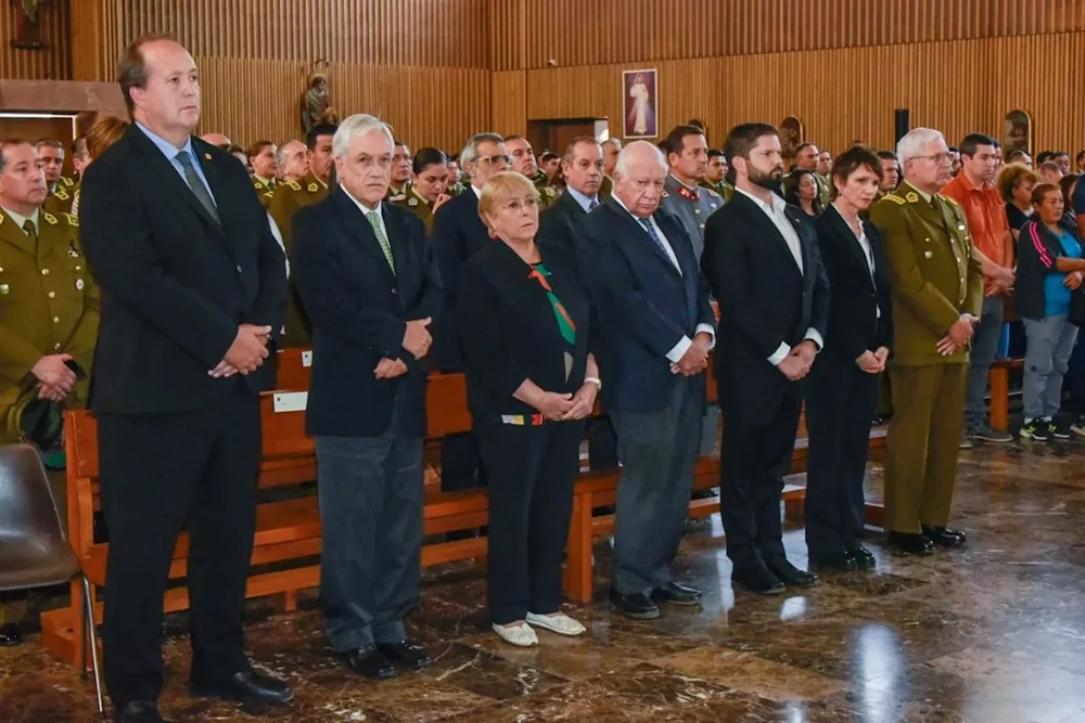 El expresidente Sebastián Piñera mira a la cámara durante el velatorio de un policía asesinado en Santiago de Chile el 6 de abril pasado. Lo acompañan los exmandatarios Michelle Bachelet y Ricardo Lagos, el actual presidente Gabriel Boric y la ministra del Interior Carolina Toha. AFP