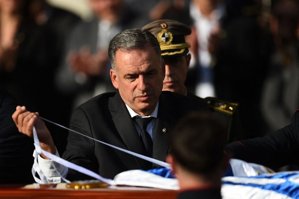 El presidente de Uruguay, Yamandu Orsi, coloca una bandera nacional en el carruaje que transporta los restos del fallecido expresidente uruguayo (2010-2015), José «Pepe» Mujica, durante el cortejo fúnebre en Montevideo, el 14 de mayo de 2025. Foto: DANTE FERNANDEZ / AFP.