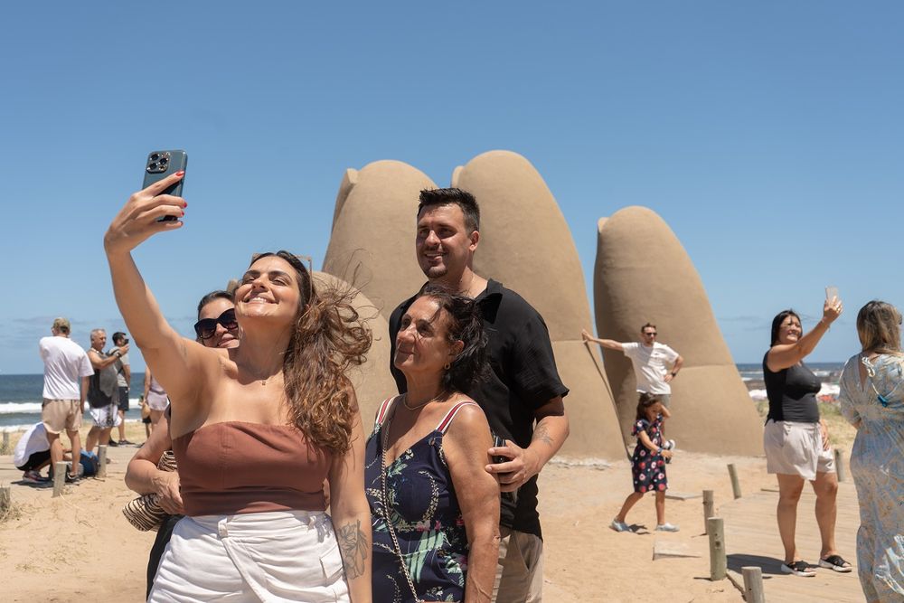 Turistas se toman fotografías junto a la escultura Los dedos este martes, en Punta del Este.&nbsp;
