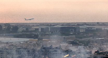 Un avión de Middle East Airlines (MEA), la aerolínea de bandera del Líbano, despega del Aeropuerto Internacional de Beirut el 6 de octubre de 2024 en medio del humo que se eleva desde los sitios cercanos que fueron blanco de ataques aéreos israelíes durante la noche en los suburbios del sur de la capital libanesa.