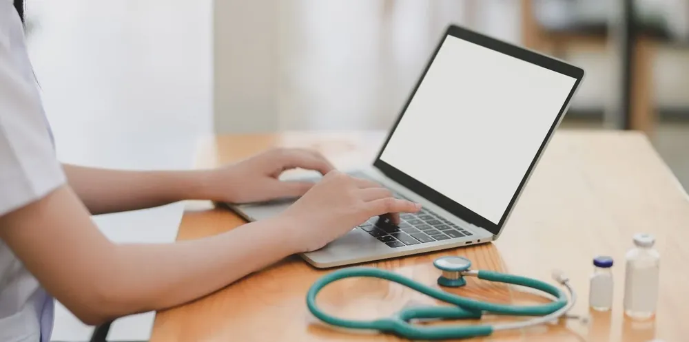 laptop-near-teal-stethoscope-in-wooden-table-3758756.webp