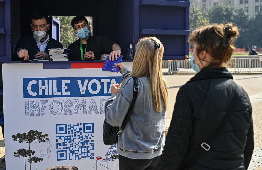 Personas reciben nuevas versiones de la Constitución chilena frente al palacio de La Moneda