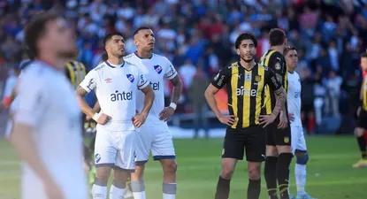 Los jugadores de Nacional y Peñarol observan mientras el partido está detenido por el enfrentamiento entre hinchas en la tribuna