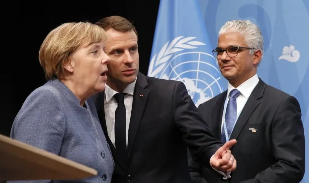 El presidente francés, Emmanuel Macron, y la canciller alemana, Angela Merkel, hablan durante la Cumbre del Clima, Alemania