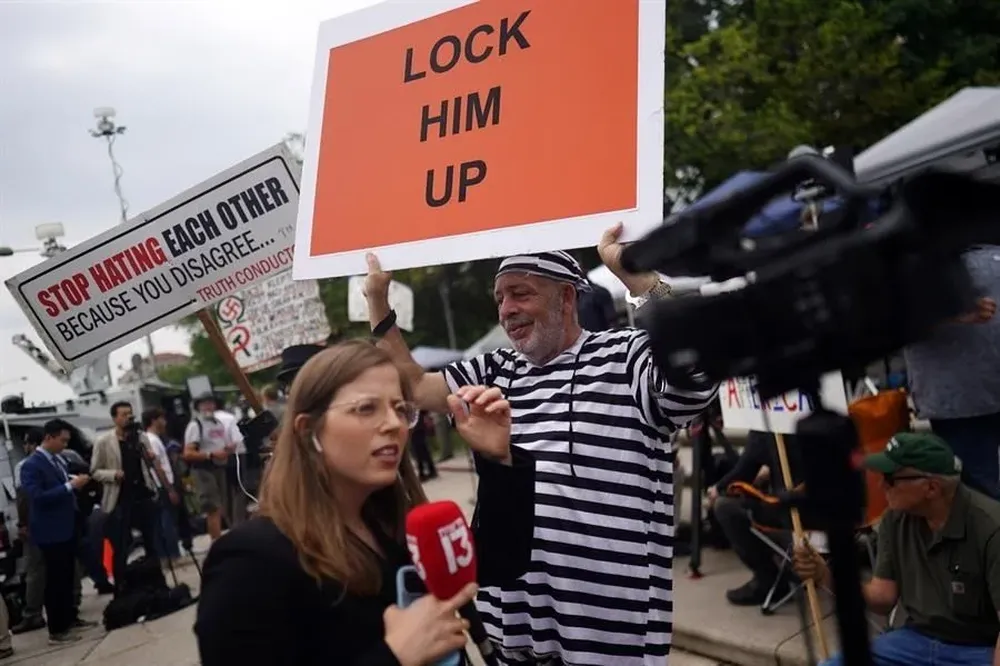 Un opositor a Trump muestra un cartel con la leyenda “Enciérrenlo”