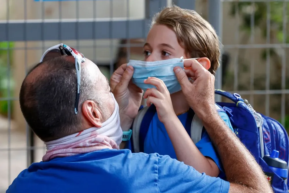 Padre le coloca un tapabocas a su hijo