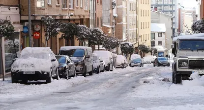 Una calle nevada con coches llenos de nieve.