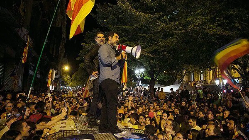 Los independentistas Sánchez y Cuixart, encima de un coche de la Guardia Civil durante los incidentes del 20 de septiembre de 2017.