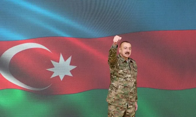 Ilham Aliyev, vestido con traje militar y levantando el puño, anuncia durante un discurso televisado a la nación la reconquista de Nagorno-Karabaj.