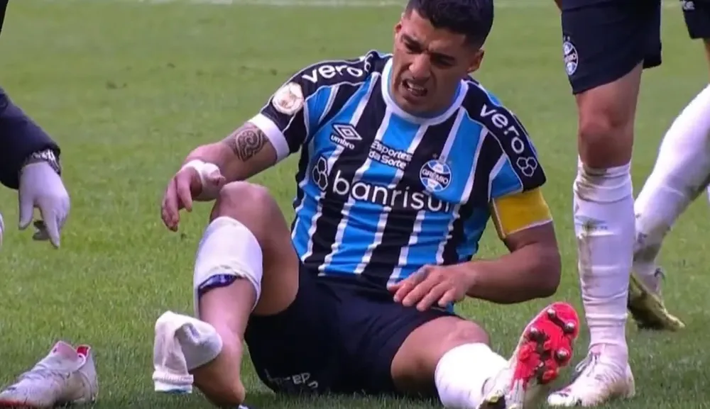 Luis Suárez en el piso y sin la media derecha por la plancha que recibió de André de Fluminense