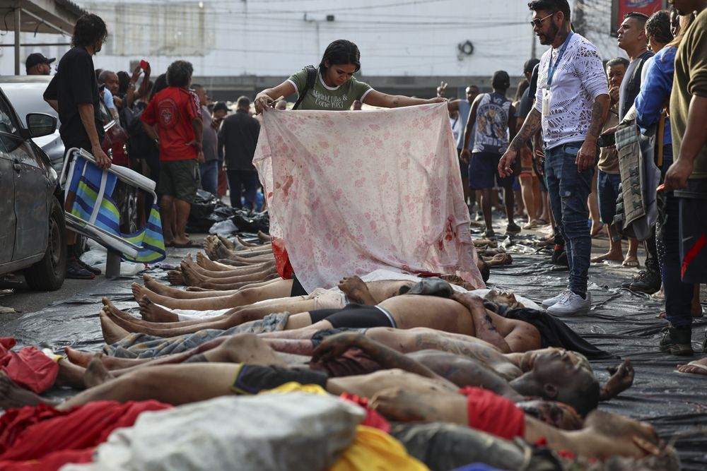 Personas observan cuerpos sin vida en una calle este miércoles, en Río de Janeiro (Brasil). El megaoperativo del martes, en el que participaron 2.500 agentes, tenía como objetivo detener a cabecillas del Comando Vermelho, una de las organizaciones criminales mas antiguas y peligrosas de Río