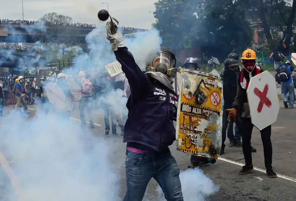 Los activistas de la oposición chocan con la policía antidisturbios en una protesta contra Nicolás Maduro.