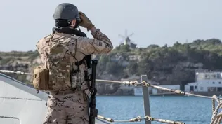 Un militar de la OTAN en la cubierta de un buque en el puerto de Mahón.