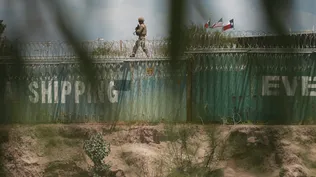 Un agente de la Guardia Nacional patrulla la frontera con México, desde lo alto de una línea de contenedores.