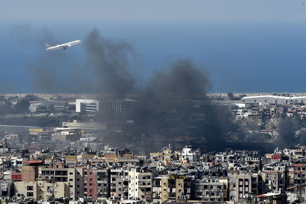 Un avión vuela en medio del humo que se eleva sobre la ciudad tras un ataque aéreo israelí en el bastión de Hizbolá en Dahieh, un suburbio al sur de Beirut, 5 de octubre de 2024.&nbsp;