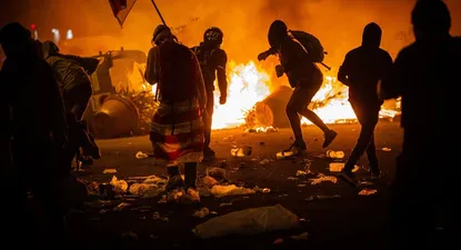 Varios manifestantes frente al fuego de una hoguera durante los disturbios en la Plaza de Urquinaona, en Barcelona a 18 de octubre de 2019.