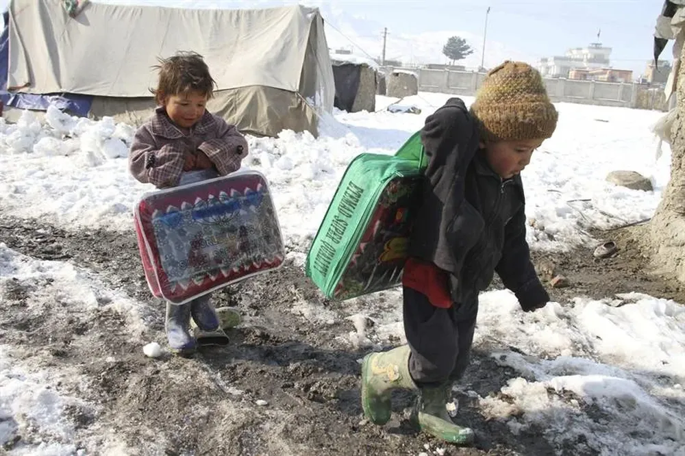 Afganistán- Un par de niños cargan con prendas de abrigo donadas por ACNUR a las afueras de Kabul
