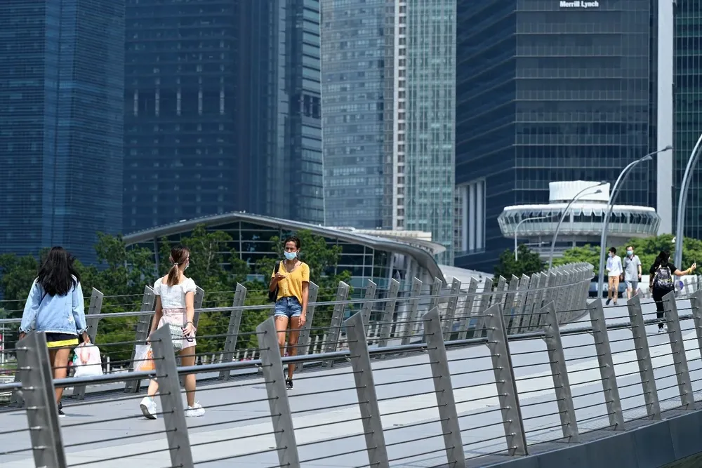 La gente camina a lo largo de un puente peatonal en el distrito financiero de Singapur, el 25 de junio de 2021