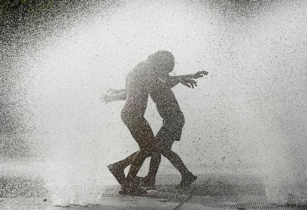 España- Varios niños se refrescan en una fuente pública de la Plaza Yamaguchi de Pamplona