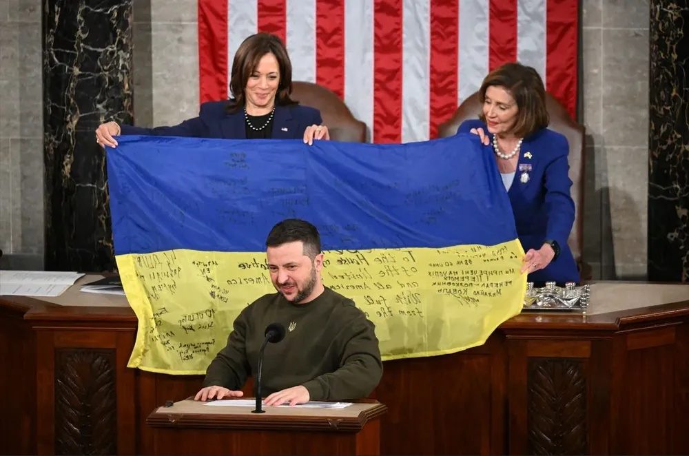 La vicepresidenta estadounidense Kamala Harris (izquierda) y la presidenta de la Cámara de Representantes Nancy Pelosi (derecha) sostienen la bandera ucraniana que el presidente Volodimir Zelensky les dio durante su discurso ante el Congreso