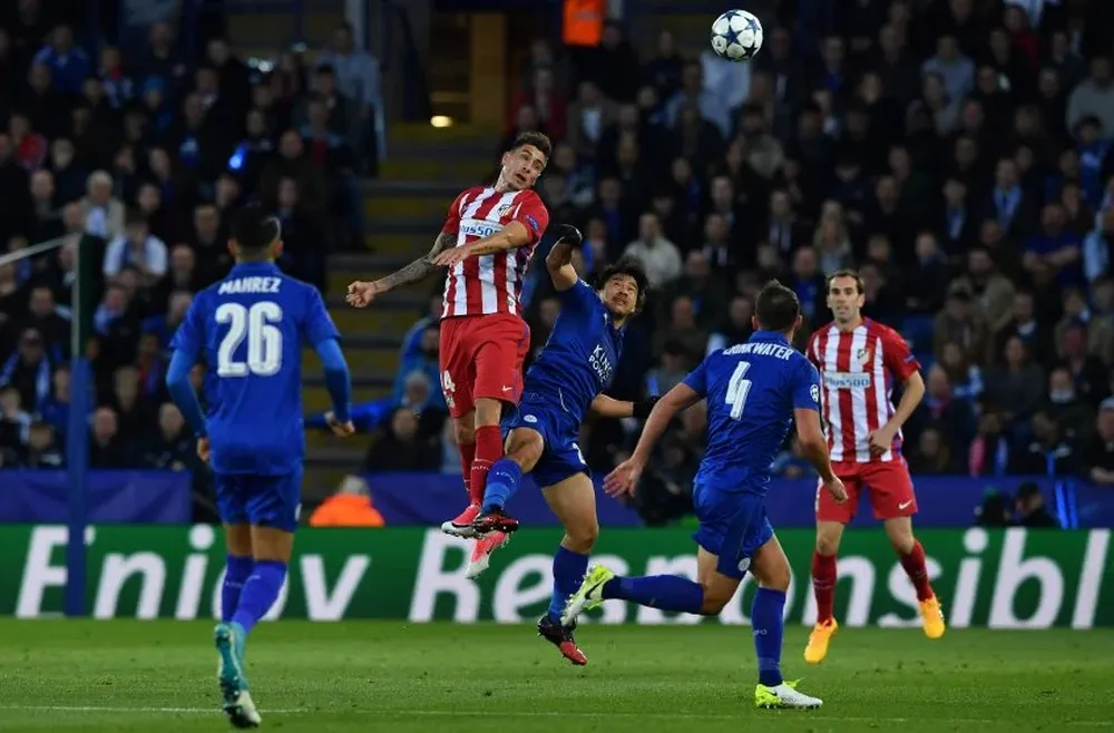 Giménez salta en el medio de Atlético y Godín lo observa