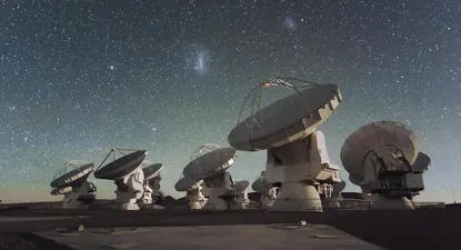 Antenas del ALMA en el llano de Chajnantor, en los Andes chilenos. La Pequeña y Gran Nube de Magallanes, dos galaxias que acompañan a la Vía Láctea, pueden observarse en el centro de la fotografía, como manchas brillantes en la noche estrellada
