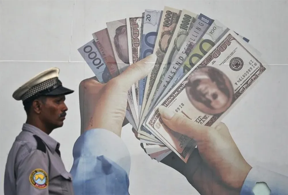 India- Un guardia de seguridad indio pasa por delante de un anuncio de cambio de monedas extranjeras en Bombay