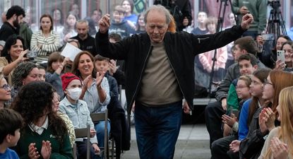 Joan Mauel Serrat junto a alumnos de un instituto en Pola de Siero que participaron de un programa cultura sobre su trayectoria. EFE