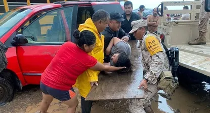 Agentes del Ejército mexicano asisten a una mujer en la península de Baja California por el paso de la tormenta tropical Hilary.