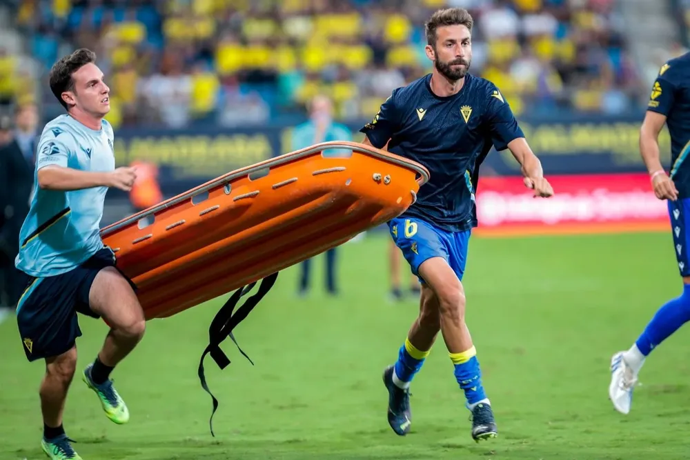 Los jugadores ayudan a llevar la camilla