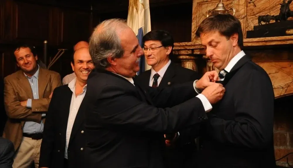 Echeverría coloca el logo de ARU en la solapa del saco del nuevo presidente