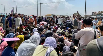 Afganos se reúnen a lo largo de una carretera mientras esperan para abordar un avión militar estadounidense para salir del país, en un aeropuerto en Kabul el 20 de agosto de 2021