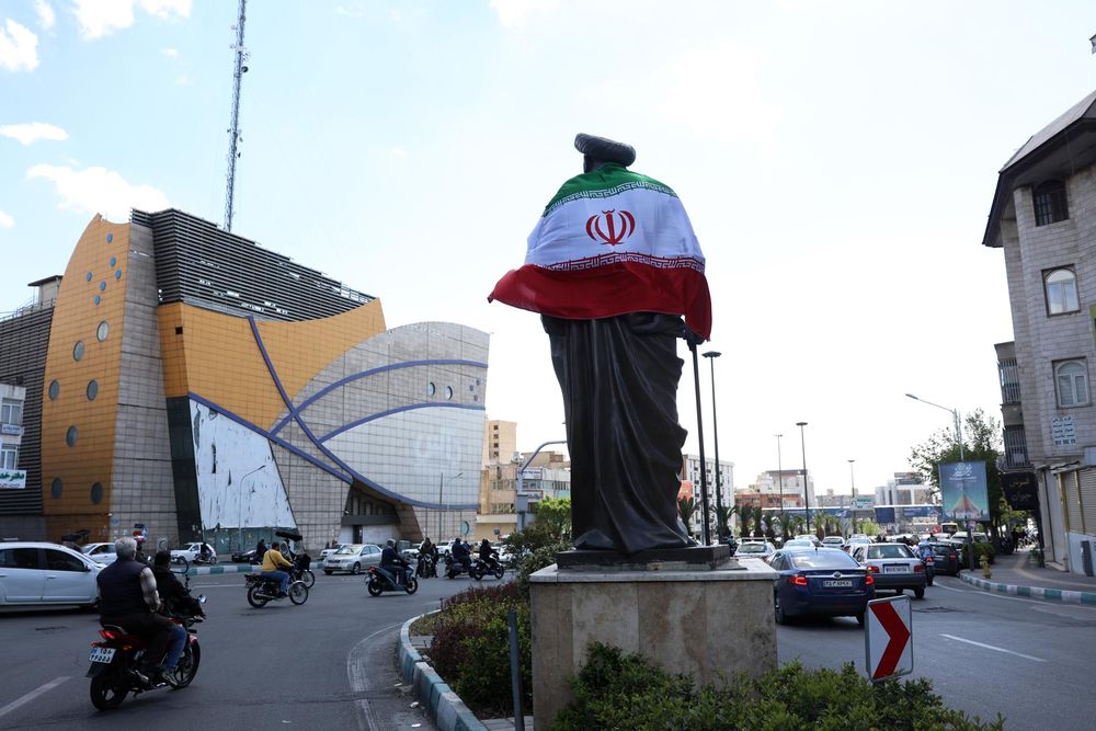 Una bandera iraní envuelve una estatua en Teherán tras el anuncio de la tregua