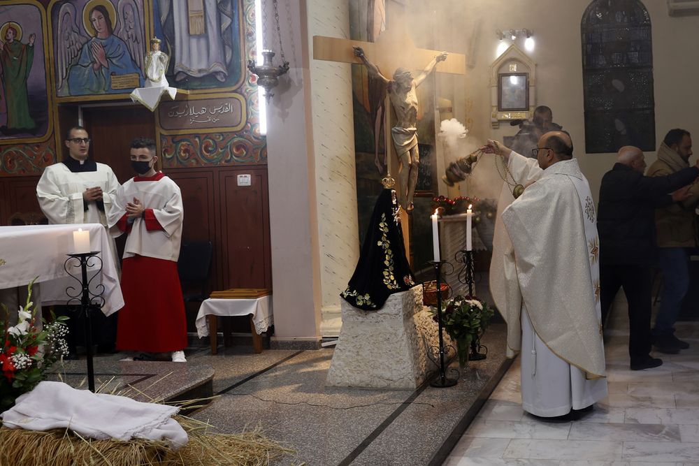 Gabriel Romanelli, párroco de la Franja de Gaza, a la izquierda, reza durante la misa del gallo en la iglesia católica de la Santa Familia en Ciudad de Gaza, el 24 de diciembre de 2021. (AP Foto/Adel Hana, Archivo)
