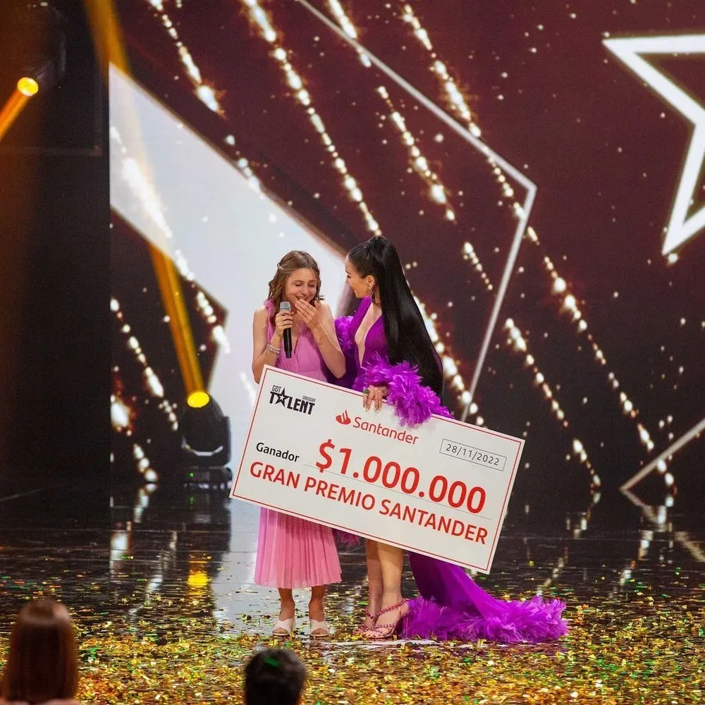 Camila Iza Machado con el cheque por un millón de pesos junto a la presentadora Natalia Oreiro