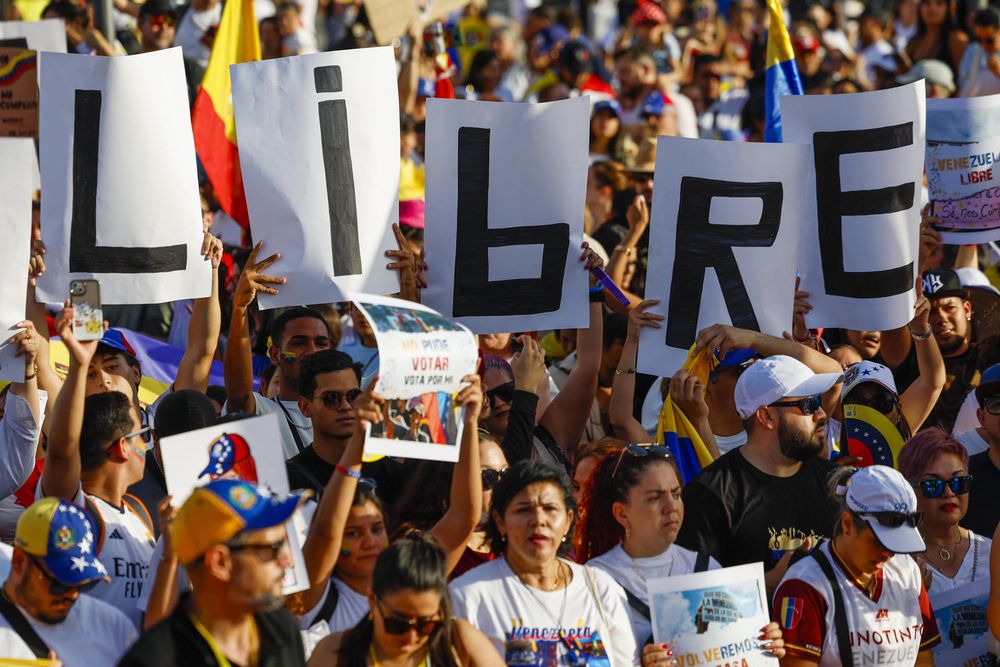 Manifestates portan un cartel con la consigna Libre en la manifestación de venezolanos en la Plaza de Colón, en Madrid