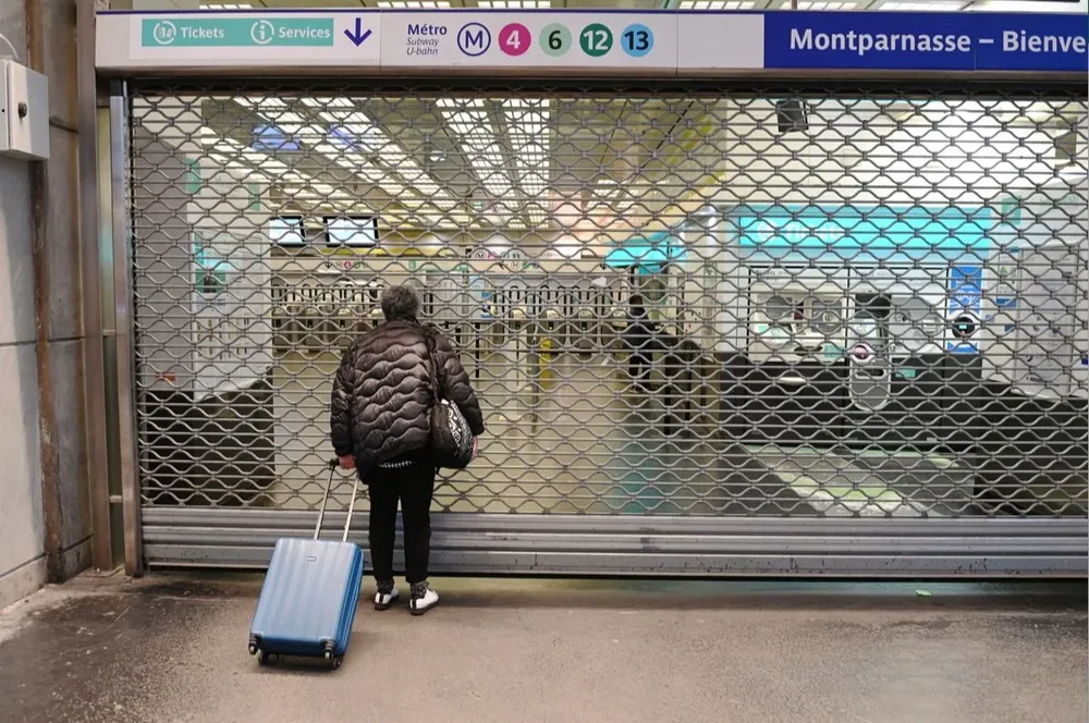 Una mujer se para frente a la puerta cerrada de una estación del metro de París