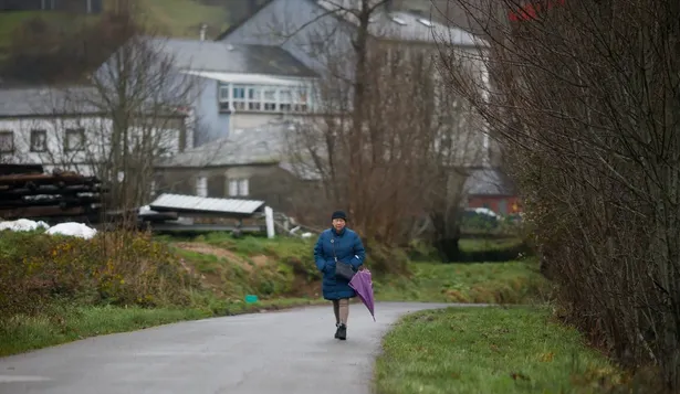 Una mujer con paraguas en un camino del municipio de Pedrafita do Cebreiro.