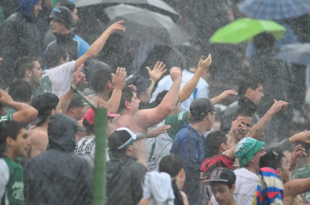 Hinchas de Racing alientan al equipo bajo la lluvia.