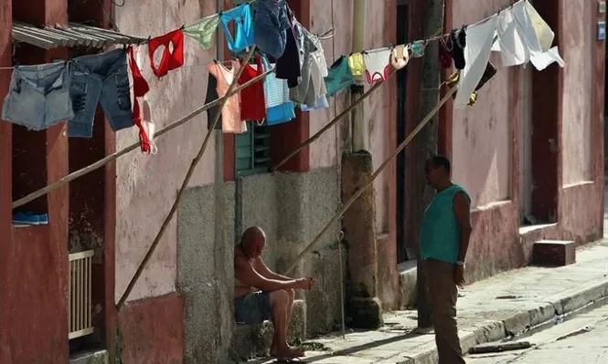 Cuba. Dos hombres conversan bajo la ropa extendida para secar, en Matanzas