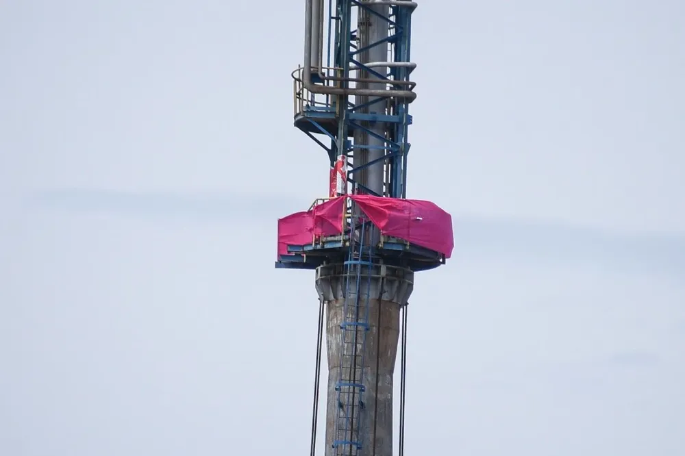 La lona rosada del Sí en lo alto de la refinería, desafiando disposiciones de seguridad