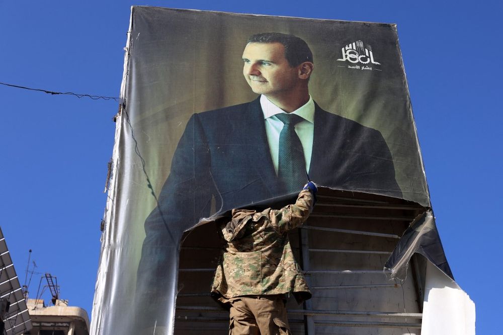 Rebeldes yihadistas descuelgan un retrato del presidente sirio, Bashar al Assad, en Alepo.