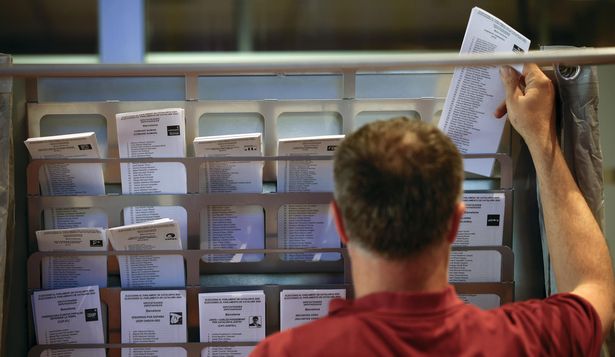 Un operario municipal coloca papeletas en una cabina en un colegio electoral en Barcelona