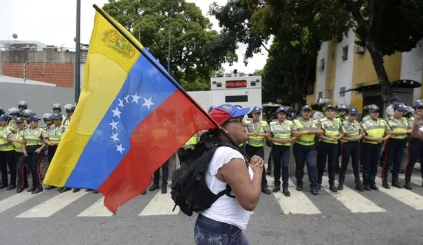 Una manifestante pasa con la bandera de Venezuela frente al cordón policial que dispuso el gobierno.