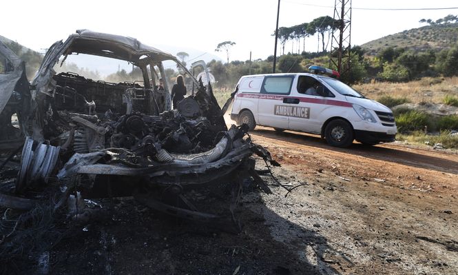 Una ambulancia pasa junto a un vehículo quemado en la localidad de Masyaf, Siria.
